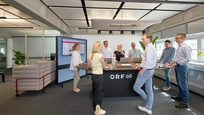 Zwei Frauen und ein Mann sitzen im Radio Studio und lächeln