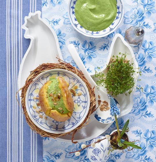 Ein kunstvoll angerichtetes Gericht mit grünem Bärlauchschaum wird auf blau-weißem Geschirr präsentiert.