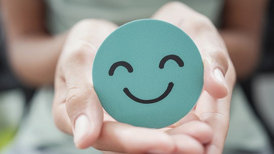 © iStock/sewcream Zwei Hände präsentieren ein rundes Smiley-Symbol in Mintgrün.