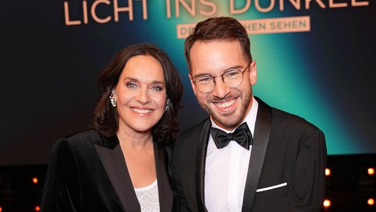 © ORF/Roman Zach-Kiesling Eva Pölzl und Andreas Onea stehen bei einer Gala vor dem Schriftzug „Licht ins Dunkel“.