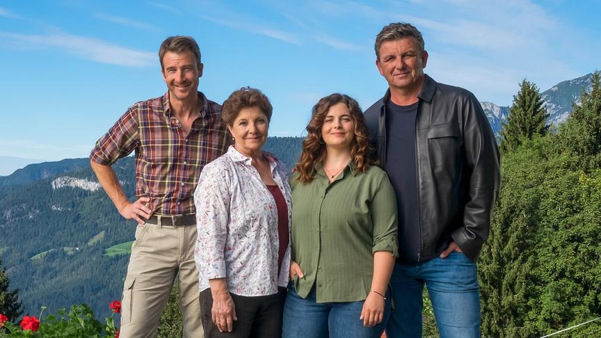  Hans Gruber, Lisbeth Gruber, Lilli Gruber und Martin Gruber stehen eng beieinander vor einer alpinen Berglandschaft und posieren im Freien bei sonnigem Wetter.