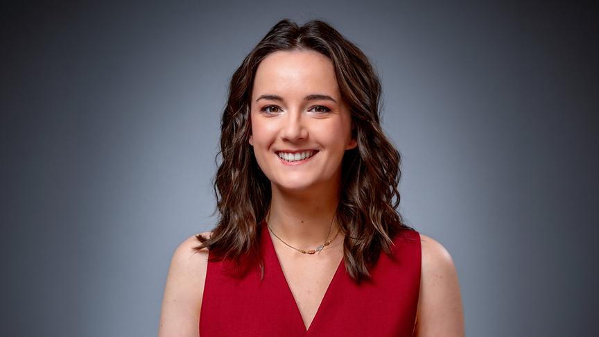 Porträt von Emily Busvine im roten Oberteil vor grauem Hintergrund