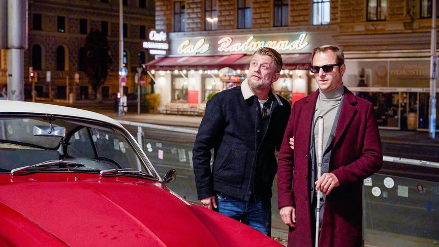 © ORF/Mona Film/Tivoli Film/Nikolaas von Schrader "Blind ermittelt - Mord an der Donau": Niko (Andreas Guenther) und Alexander Haller (Philipp Hochmair) stehen bei ihrem Auto vor dem Volkstheater.