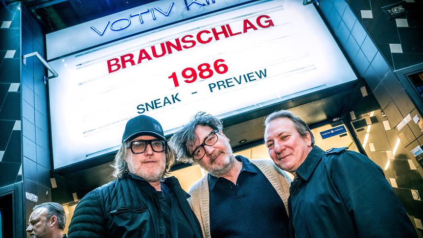 © ORF/Thomas Jantzen Nicholas Ofczarek, Regisseur und Produzent David Schalko und Robert Palfrader posieren abends vor dem Votiv-Kino, über dem auf einer Leuchttafel „Braunschlag 1986 – Sneak Preview“ zu lesen ist.