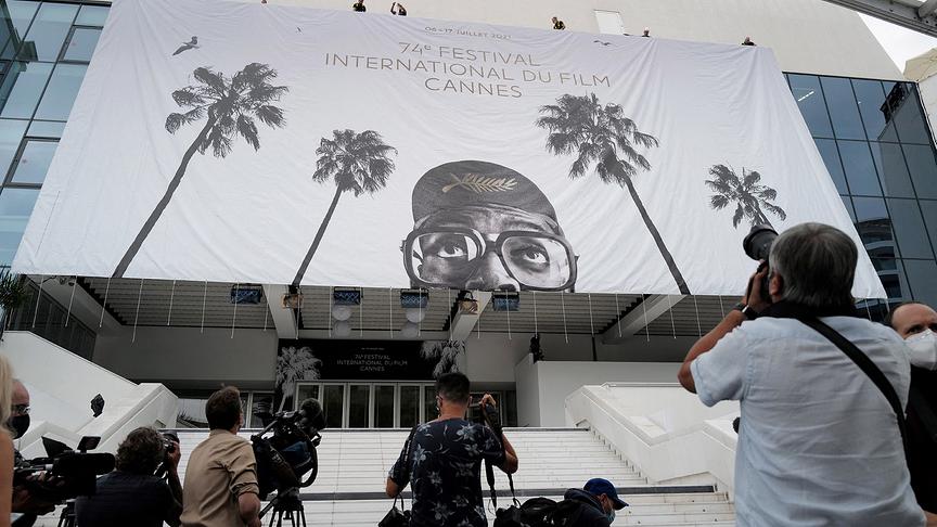 © APA/AFP/Valery HACHE Journalists take images as workers install a giant banner at the Palais des Festivals et des Congres in Cannes, southeastern France, on July 4, 2021, two days before the start of the 74th Cannes Film Festival.