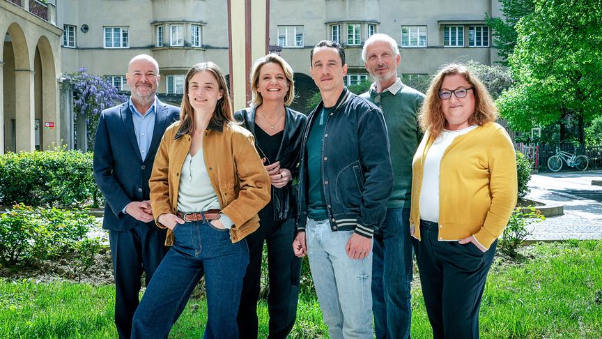 Gruppenfoto mit Produzent Markus Pauser, Miriam Fussenegger, ORF-Programmdirektorin Stefanie Groiss-Horowitz, Laurence Rupp, Bernhard Natschläger und ORF-Fernsehfilmchefin Katharina Schenk beim „Tatort“-Setbesuch , vor einem Wohnhaus und umgeben von Grünflächen.