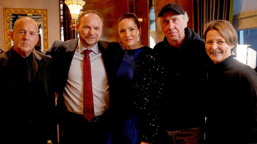 Gruppenfoto zum Drehstart für ORF/ARD/SRF-Dokudrama „Benko – Size does matter“ (AT) mit Heino Ferch, Thomas Stipsits, Patricia Aulitzky, Regisseur Raymond Ley und Bettina Weiguny in einem elegant beleuchteten Innenraum.