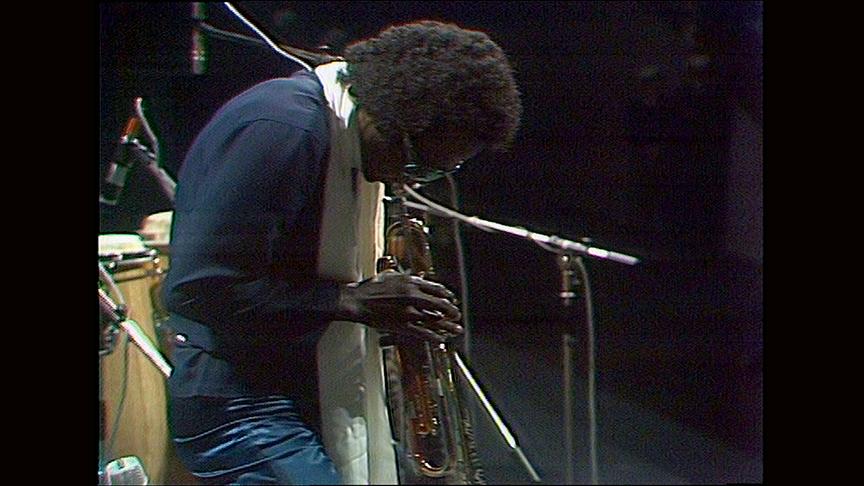 Miles Davis spielt Trompete auf einer Bühne mit gesenktem Kopf