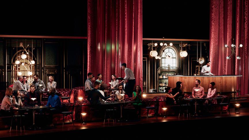 Kaffeehaus-Charme im Green Room mit roten Samtvorhängen und -sofas, in dem Gäste an kleinen Tischen sitzen, bedient von Servicepersonal, mit einer stilvollen Bar im Hintergrund.