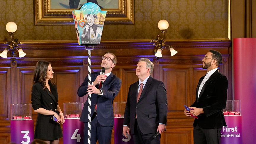 Alexandra Maritza Wachter, Conradin Cramer (Regierungspräsidenten der Stadt Basel) mit der Fasnachtslaterne, Michael Ludwig (Bürgermeister der Stadt Wien), Cesár Sampson stehen gemeinsam auf der Bühne bei der  Auslosungszeremonie.