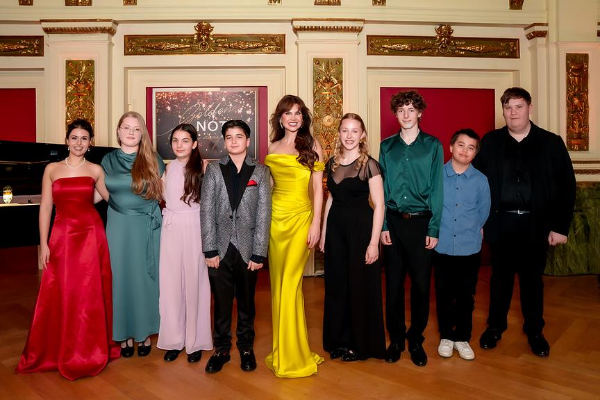 Leona König steht mit den "Goldene Note"-Finalistinnen und Finalisten Idil Naz Alici, Julie Herber, Maria Bendel, Amadeus Jánoška, Leona König, Linda Gittmaier, Adam Benold, Lukas Maierhofer und Nico Haidenhofer in einem prunkvollen Saal mit goldenen Verzierungen.