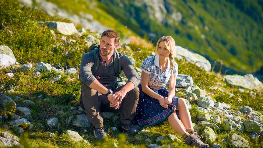 © ORF/Graf Film/Thomas Weilguny Ben und Melanie machen eine Pause im alpinen Gelände bei Sonnenschein und sitzen nebeneinander auf felsigem Berggelände.