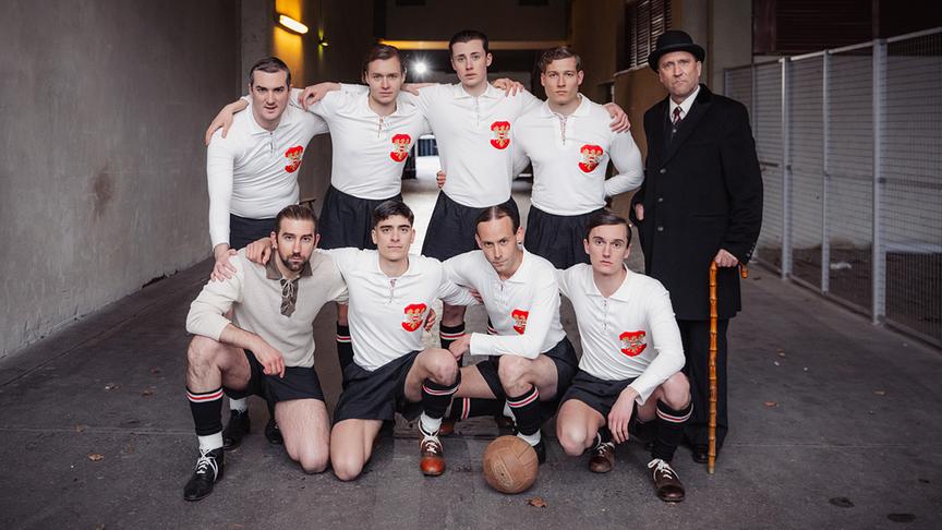 © ORF/Rizar.Photo/Gabriel Alarcon Das Wunderteam in historischen Fußballtrikots mit Trainer Hugo Meisl im Mantel mit Hut und Gehstock posiert im Stadion Gang (Praterstadion).