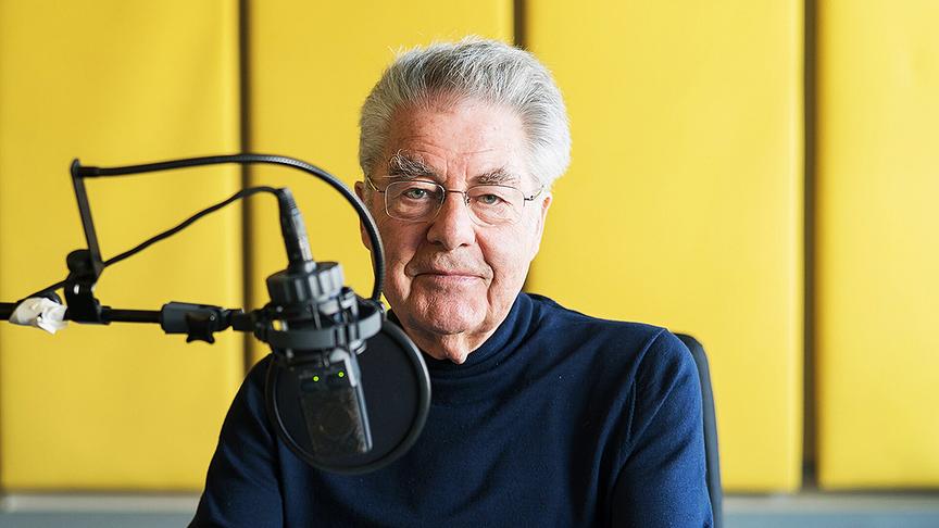 Heinz Fischer, Bundespräsident a.D.,  sitzt vor einem Mikrofon in einem Studio mit gelber Wand.