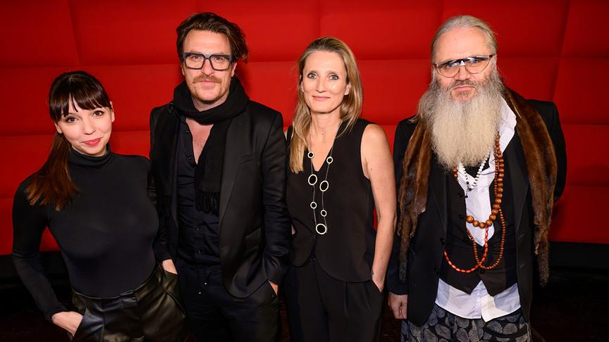 © ORF/Hans Leitner Gruppenfoto mit ORF-Moderatorin Lillian Moschen, Parov Stelar alias Marcus Füreder, Regisseurin Tatjana Berlakovich und Performancekünstler Patrick Huber bei der Kinopremiere vor rotem Hintergrund.