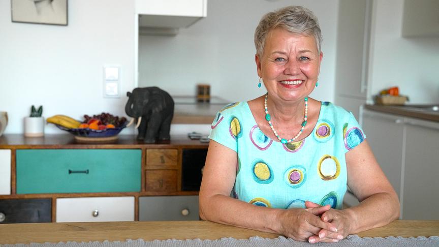 © ORF/Talk TV/Gustl Gschwantner Jascha, 72, mit kurzem grauem Haar sitzt lächelnd an einem Tisch in einer hellen Küche.