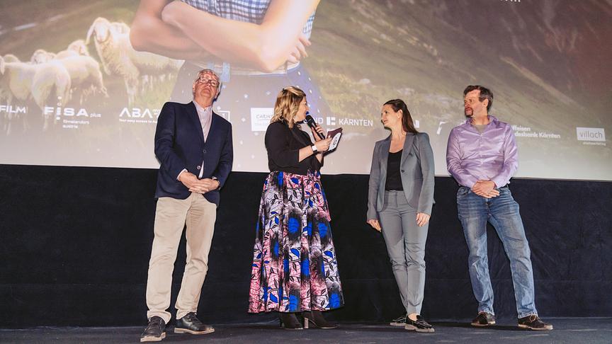 © ORF/Stadtmarketing Villach/Marta Gillner Produzent Klaus Graf, Moderatorin Elisabeth Puschan, Produzentin Livia Graf-Bechler und Produzent Viktor Perdula auf der Bühne bei der Sneak-Preview von „Herzklang – Zurück zu mir“ im Stadtkino Villach.