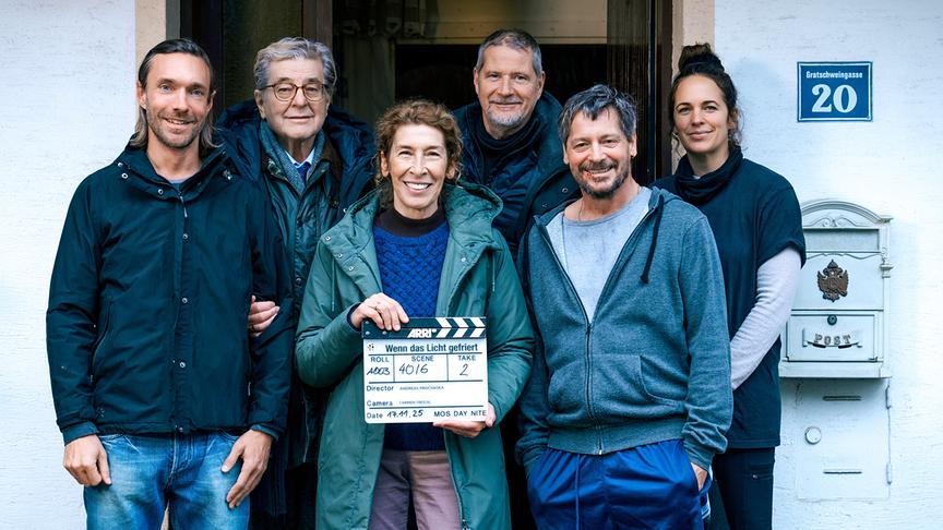© ORF/Gebhardt Productions/Petro Domenigg Gruppenfoto mit Christoph Luser, Erwin Steinhauer, Adele Neuhauser, Regisseur Andreas Prochaska, Fritz Karl und Kamerafrau Carmen Treichl vor einem Hauseingang. Adele Neuhauser hält Filmklappe mit Aufschrift „Wenn das Licht gefriert“.