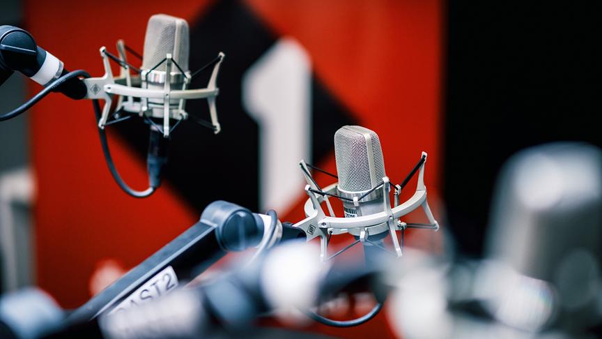 © ORF/Hans Leitner Zu sehen sind mehrere professionelle Studiomikrofone an Halterungen in einem modernen Radiostudio mit dem Ö1-Logo im Hintergrund.
