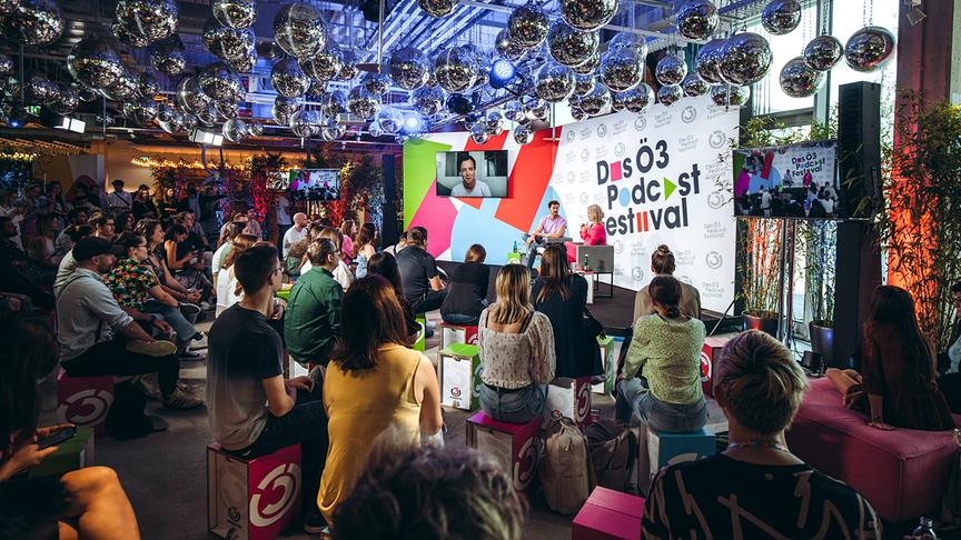 © ORF/Hitradio Ö3/Mila Zytka Ö3-Podcast-Festival mit Publikum und einer Live-Talkrunde auf einer Bühne mit vielen Discokugeln darüber