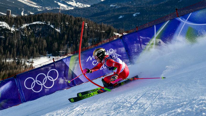 © APA/AFP/Stefano RELLANDINI Die Österreicherin Katharina Truppe fährt bei einem Olympia-Slalom in Schräglage um ein Tor und wirbelt dabei eine große Schneefahne auf, vor alpiner Bergkulisse bei den Olympischen Winterspielen Mailand-Cortina 2026 im Tofane Alpinen Skizentrum in Cortina d’Ampezzo
