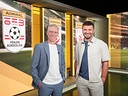  Peter Stöger und Thomas Seidl stehen im Studio von „Fußball am Sonntag“ vor einer Wand mit Admiral-Logos der Frauen-Bundesliga.