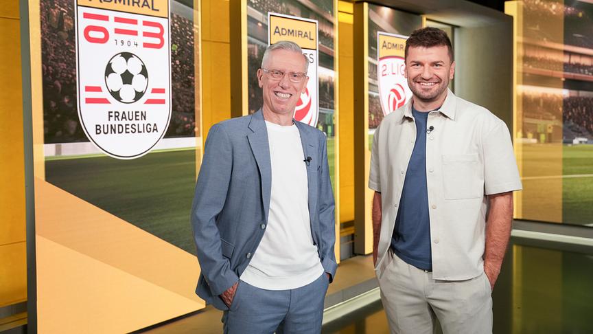  Peter Stöger und Thomas Seidl stehen im Studio von „Fußball am Sonntag“ vor einer Wand mit Admiral-Logos der Frauen-Bundesliga.