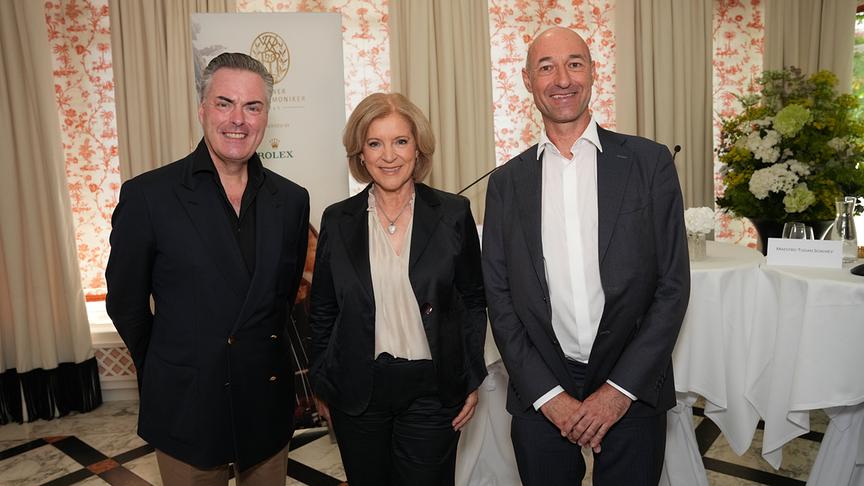 Daniel Froschauer, Ingrid Thurnher und Michael Bladerer posieren lächelnd im Rahmen der Vertragsunterzeichnung in einem elegant dekorierten Raum.