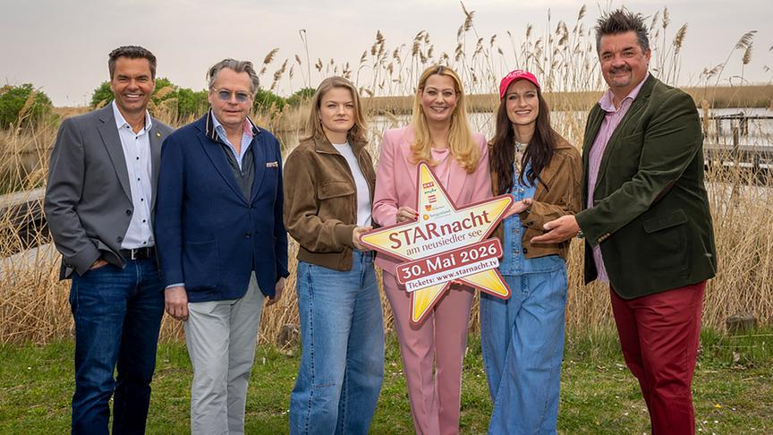 Gruppenfoto mit Didi Tunkel, Martin Gastinger, Caro Fux, Daniela Winkler, Die Mayerin und Gerfried Zmölnig  im Freien vor Schilf mit einem großen Stern‑Schild, das für die „Starnacht am Neusiedler See“ am 30. Mai 2026 wirbt.