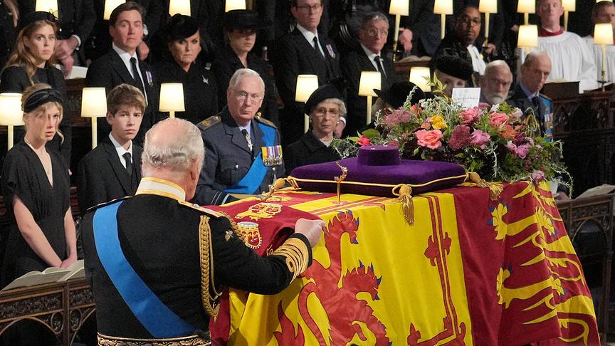 Britain's King Charles III places the the Queen's Company Camp Colour of the Grenadier Guards on the coffin during the Committal Service for Britain's Queen Elizabeth II in St George's Chapel inside Windsor Castle on September 19, 2022