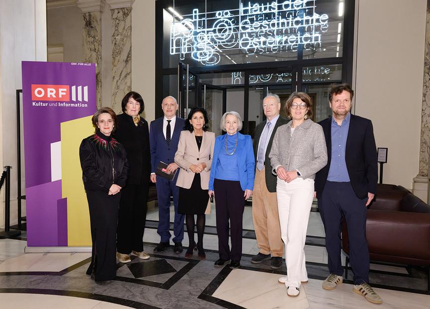 Gruppenfoto mit Eva Nowotny, Andreas Pfeifer, Danielle Spera, Anneliese Rohrer, Andreas Khol, Monika Sommer und Ernst Pohn im Eingangsbereich des Hauses der Geschichte Österreich neben einem ORF-III-‑Kultur‑und‑Information‑Banner.