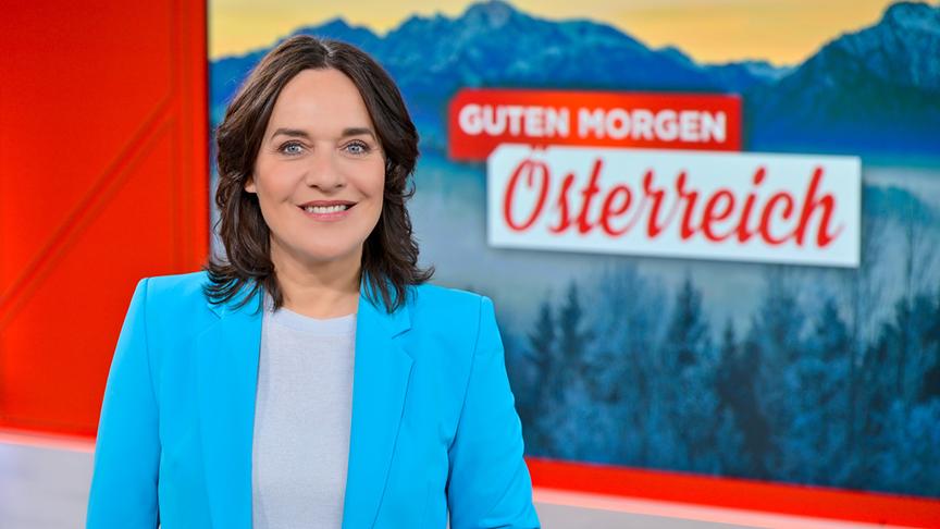 Eva Pölzl steht im Fernsehstudio vor einem Sujet mit Berglandschaft und dem Schriftzug „Guten Morgen Österreich“.