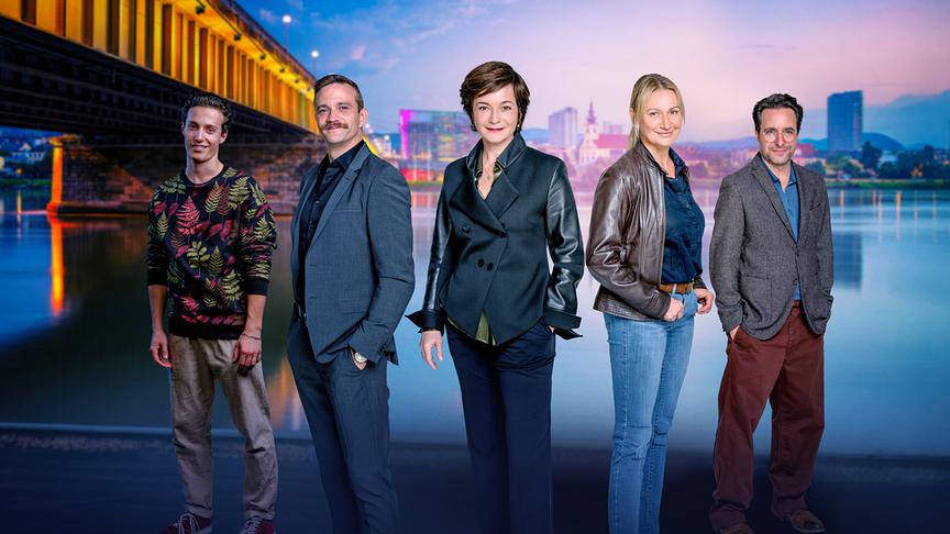 Das "Soko Linz"-Team Damyan Andreev, Michael Steinocher, Katharina Stemberger, Angelika Niedetzky und Alexander Pschill stehen vor einer abendlichen Stadt- und Flusskulisse nebeneinander und blicken in Richtung Kamera.
