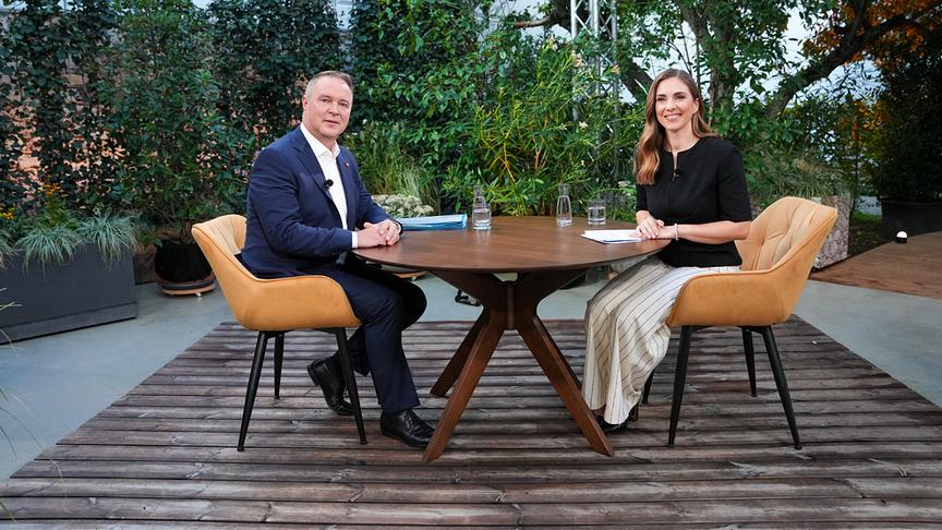 © ORF/Roman Zach-Kiesling Andreas Babler und Simone Stribl sitzen an einem Tisch im begrünten Außenstudio der ORF-"Sommergespräche 2026"