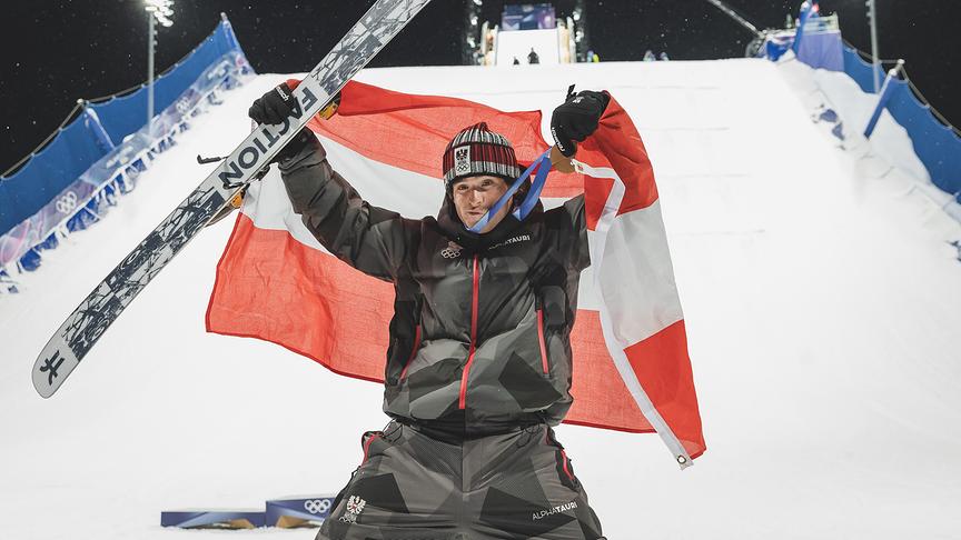 Bronzemedaillengewinner Matej Svancer  jubelt im Zielbereich, hält seine Medaille und einen Ski in die Höhe und schwenkt eine österreichische Flagge, während der Medaillenzeremonie für den Freeski Big Air Bewerb der Männer im Rahmen der Olympischen Winterspiele in Livigno.