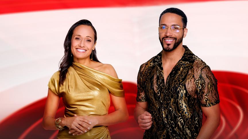 Alice Tumler und César Sampson in eleganter Kleidung stehen vor einem rot‑weiß gehaltenen Hintergrund.