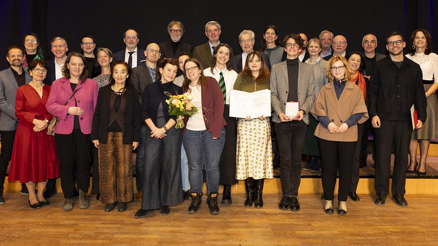 © ORF/Ö1/Michaela Obermair Gruppenfoto mit den Preisträger*innen des „Radiopreises der Erwachsenenbildung 2025" auf einer Bühne vor schwarzem Hintergrund