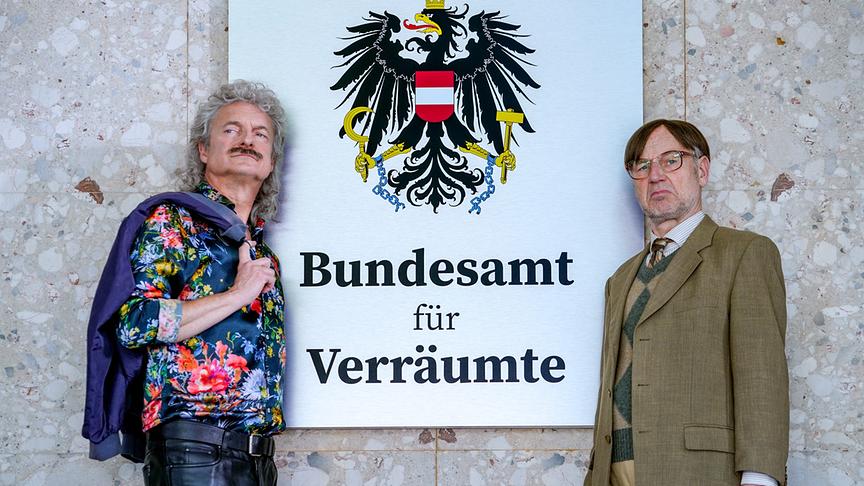 Alfred Dorfer und Roland Düringer stehen vor dem Schild vom "Bundesamt für Verräumte"