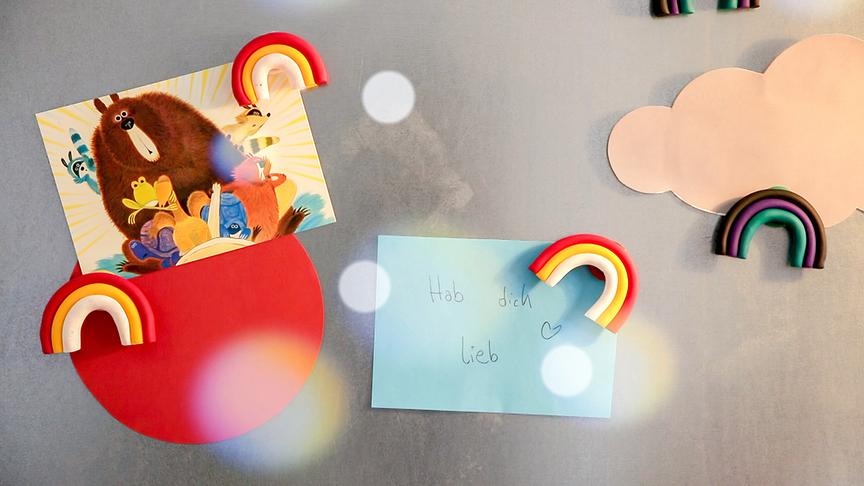 © ORF/Tower10 Eine liebevoll gestaltete Wanddekoration zeigt bunte Regenbogenmagnete, eine Wolke, eine Kinderillustration und einen Zettel mit der handgeschriebenen Botschaft „Hab dich lieb“.