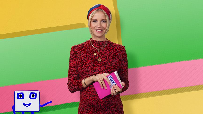 © ORF/Diorama Films Fanny steht mit einem Buch in der Hand in einem bunt gestalteten Studiohintergrund.