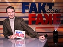 In einem Fernsehstudio sitzt lächelnd Moderator Clemens Maria Schreiner am Moderatorenpult vor dem Schriftzug „FAKT oder FAKE“.