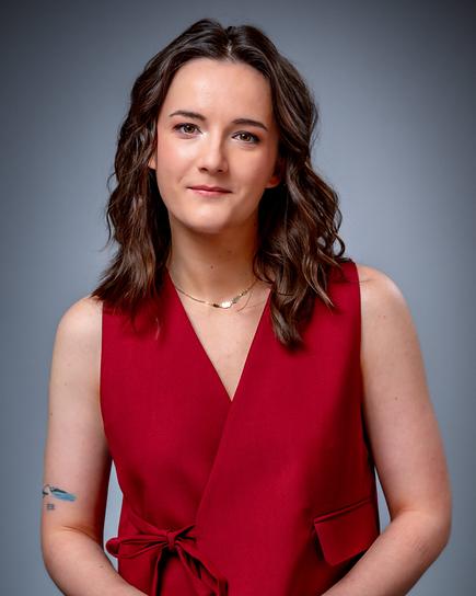 Porträt von Emily Busvine im roten Oberteil und roter Hose vor grauem Hintergrund