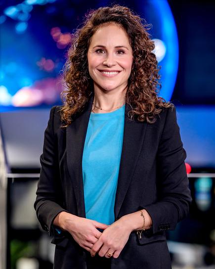 Ruth Hutsteiner, Moderatorin des "ZIB Magazin Klima" steht in einem modernen Newsroom vor einer großen Bildschirmwand