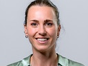 Viktoria Schnaderbeck hält lächelnd vor neutralem Hintergrund ein Mikrofon in die Kamera.