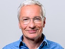 Porträtfoto von Rainer Pariasek vor grauem Hintergrund