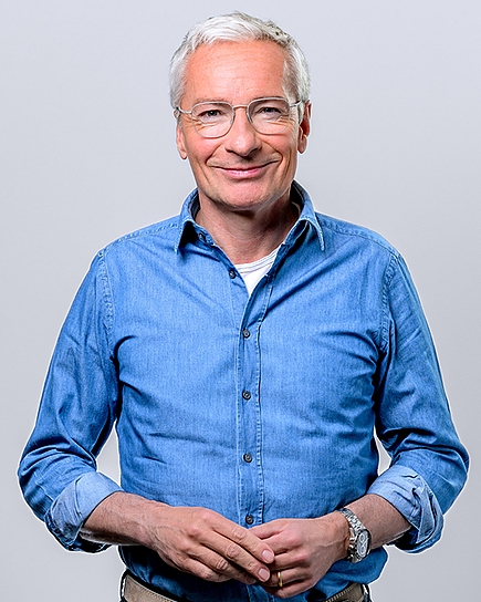 Porträtfoto von Rainer Pariasek vor grauem Hintergrund